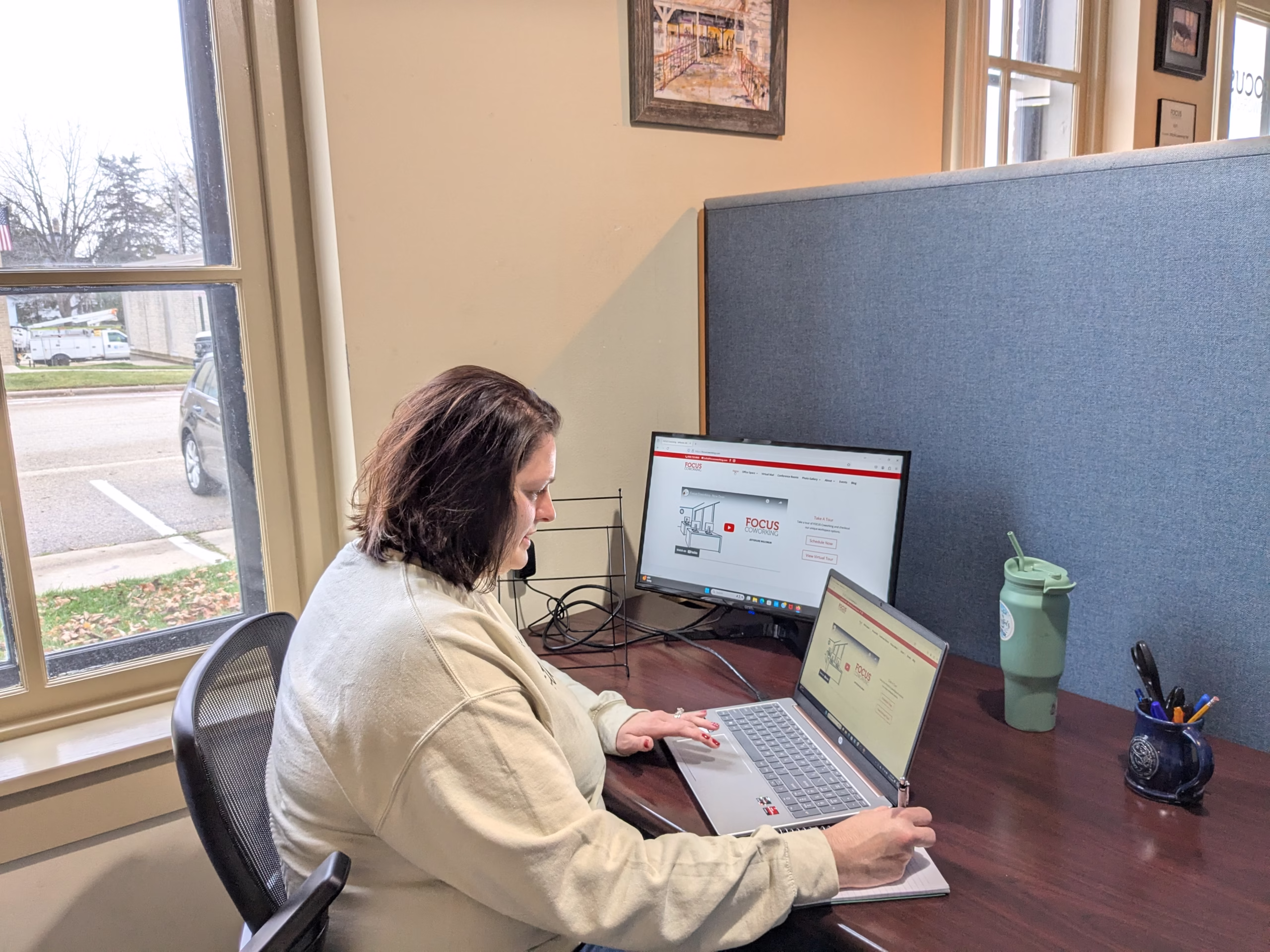 A FOCUS Coworking member doing work on her laptop at a desk.
